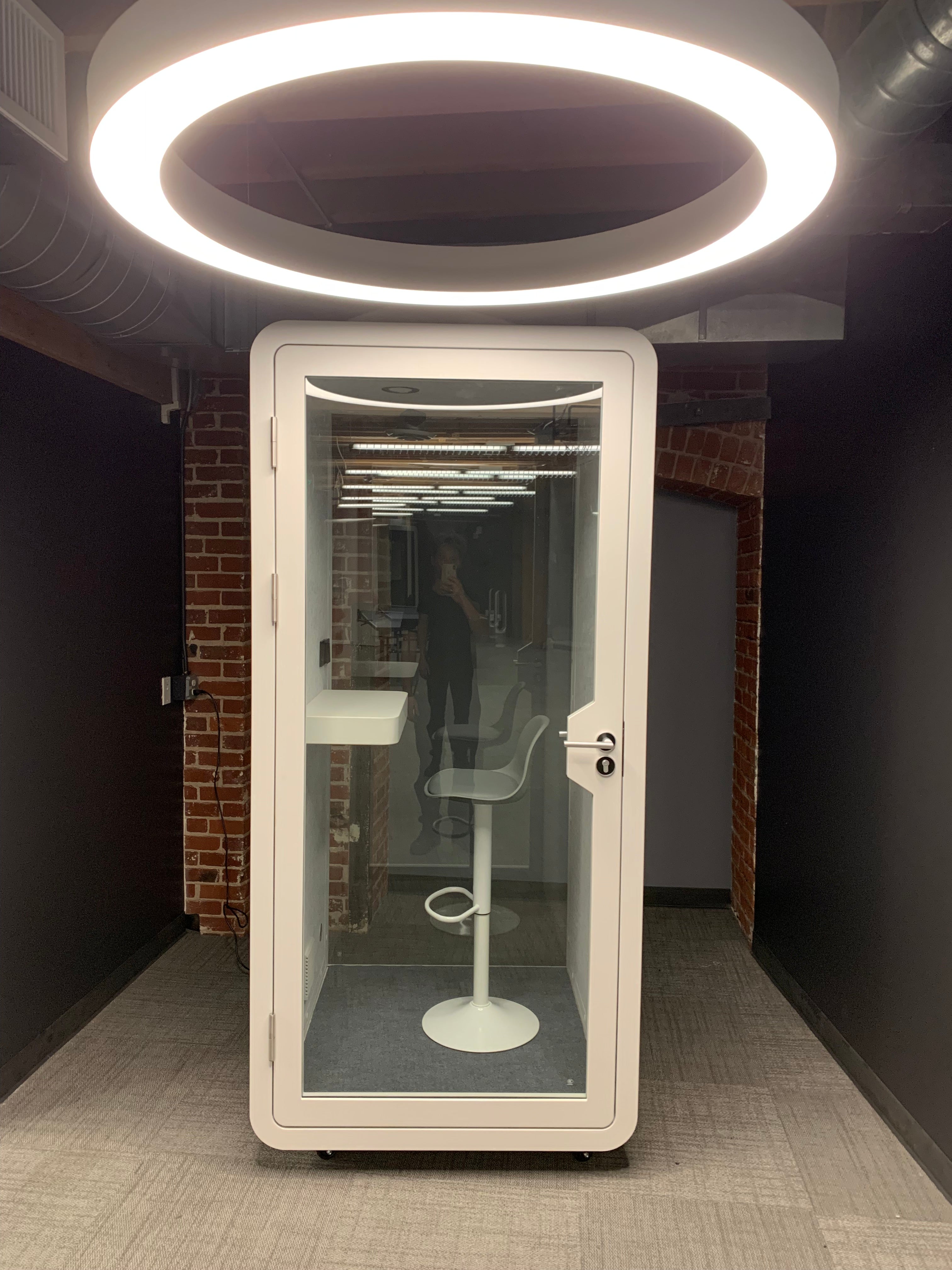 eBooth Solo office phone booth showcased under a halo chandelier